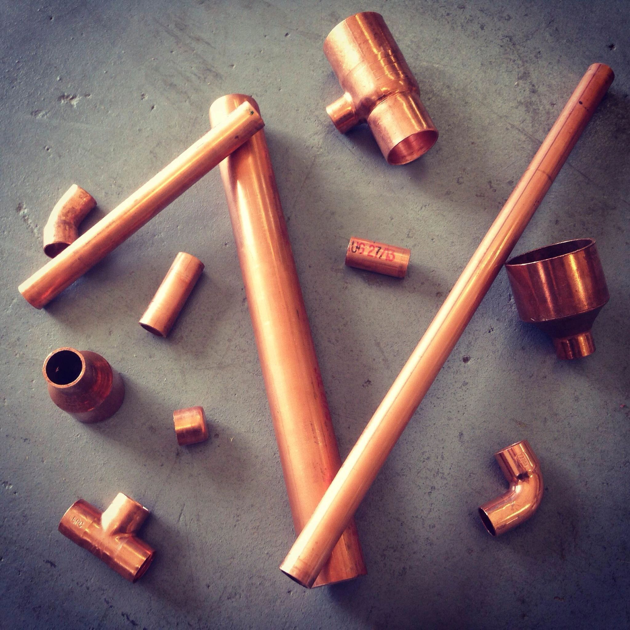 Various copper pipes and fittings on a concrete surface.